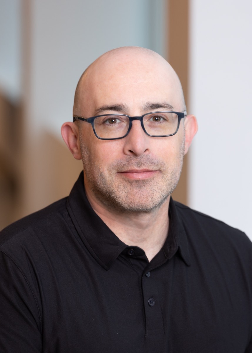 Portrait of a man with glasses in a black polo shirt